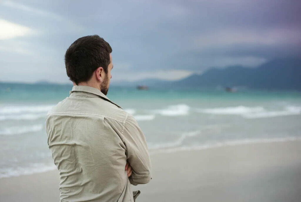 man looking at ocean feeling grief