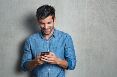 man smiling while looking at his phone