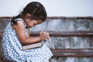 a child in polka dots dress praying