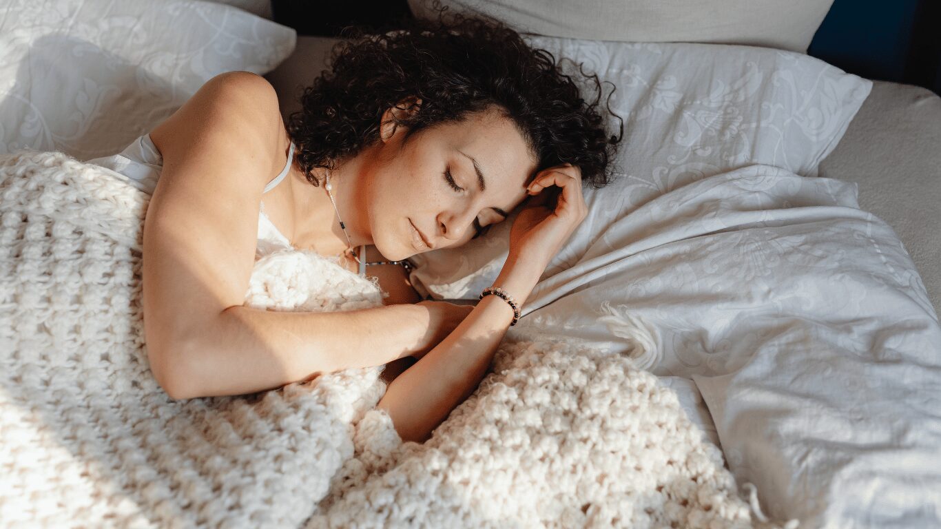 A person peacefully sleeping in a bed covered by a soft blanket